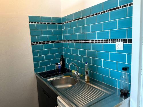 une salle de bain avec un lavabo et un mur carrelé bleu dans l'établissement Le Galion, à Saint-Hilaire-de-Riez