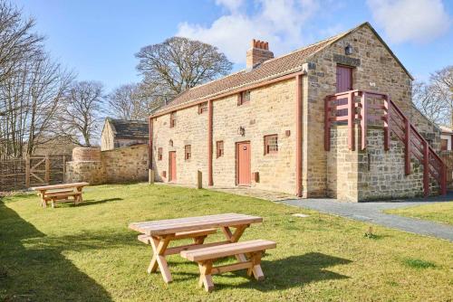two picnic tables in front of a brick building at Host & Stay - Beamish Museum Cottages in Beamish