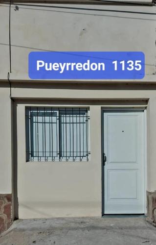 Un edificio con una puerta blanca y un cartel en ella. en Alojamientos en Curuzu Cuatia, en Curuzú Cuatiá