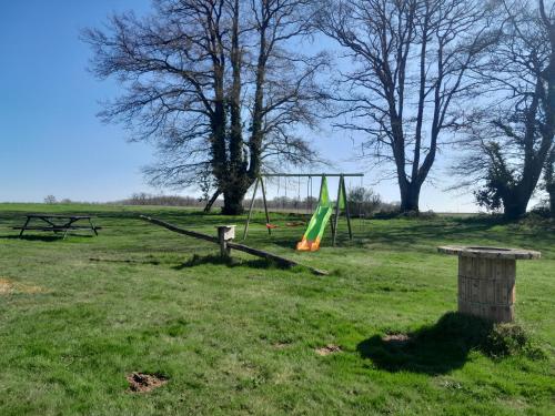 a park with a playground with a swing at Gîtes à l'ombre des chênes in Châteauvieux