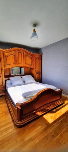 - un grand lit dans une chambre avec un cadre en bois dans l'établissement La perle du Jura, à Champagnole