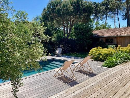 two chairs sitting on a deck next to a swimming pool at Villa Madonne - Piscine - Plage in Lège-Cap-Ferret