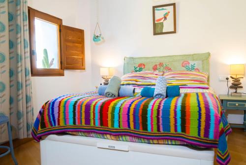 Un dormitorio con una cama con una manta colorida. en Casa Vilamurada - Duplex frente Castillo Dénia - By Marina Alta Holidays, en Denia