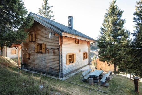 an old wooden house with a couch in front of it at Feriendorf Koralpe Chalet Speik XL 27 in St. Gertraud