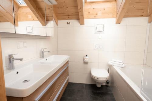 a bathroom with a sink and a toilet and a tub at Feriendorf Koralpe Chalet Speik XL 27 in St. Gertraud