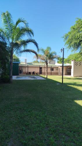a building with a palm tree in front of a field at Finca la milagrosa in Santiago del Estero