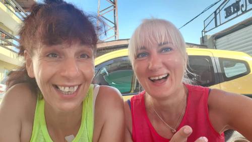two women posing for a picture in front of a car at Enjoy Guest House in Golden Sands