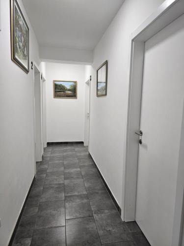 a hallway with white walls and a tile floor at Filipovic rent a car & apartments in Selnica Šćitarjevska