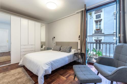 a bedroom with a bed and a chair and a window at Charming 4 Double Bed Steps from the Old Town in Bilbao
