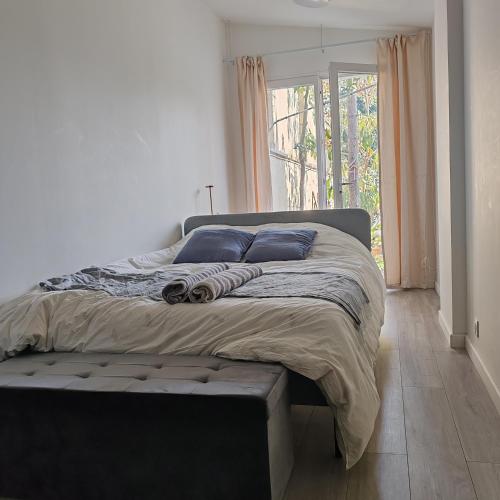 - une chambre avec un grand lit doté d'oreillers bleus et d'une fenêtre dans l'établissement Jardin Briand, à Champigny-sur-Marne