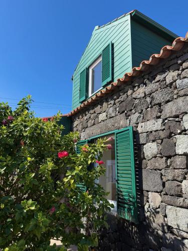 a stone building with a green window and a bush at Musa do Pico in Madalena