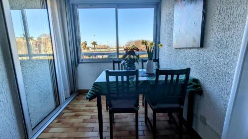 une salle à manger avec une table et des chaises et une fenêtre dans l'établissement 049 Beau studio cabine quartier falaises avec parking, au Cap d'Agde