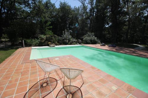 una piscina con due sedie di fronte di La cabane des bords d'Ariège a Grépiac