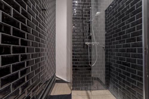 La salle de bains est pourvue d'une douche et de murs en briques noires. dans l'établissement Royal Suite - Villeurbanne centre, à Villeurbanne