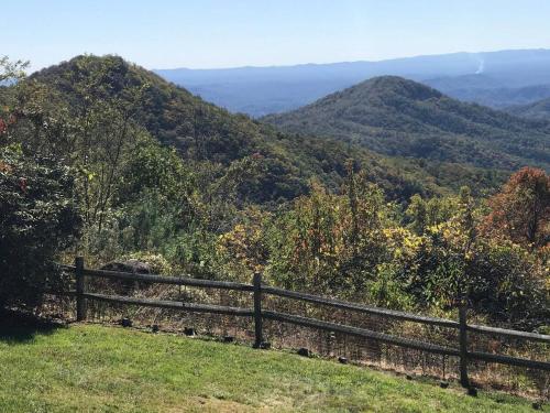 a fence on a hill with mountains in the background at Elkstone Panoramic Views from Blowing Rock to Grandfather in Blowing Rock
