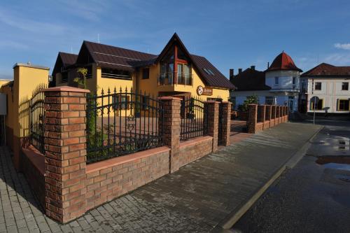 une clôture en briques devant une maison jaune dans l'établissement Penzion Anesis - štúdiá, à Turčianske Teplice