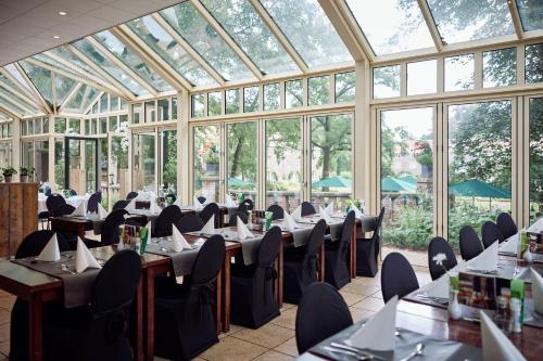 a dining room with tables and chairs in a conservatory at Landgoed Ehzerwold in Almen