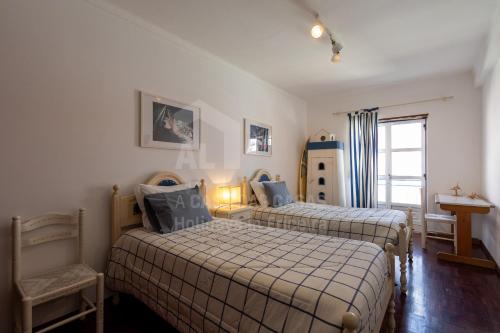 Un dormitorio con dos camas y una ventana. en Solazur by ACasaDasCasas, en Ericeira