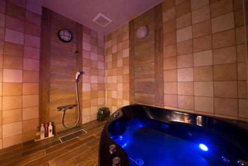 a bathroom with a blue tub and a clock at ホテル ランドランド -Adult Only- in Yamatotakada