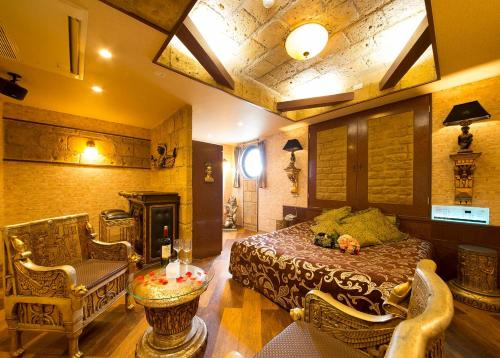 a bedroom with a bed and chairs and a fireplace at ホテル ランドランド -Adult Only- in Yamatotakada