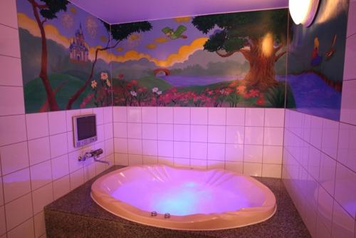 a bathroom with a bath tub with a painting on the wall at ホテル ランドランド -Adult Only- in Yamatotakada