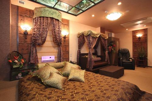 a bedroom with a large bed and a chair at ホテル ランドランド -Adult Only- in Yamatotakada