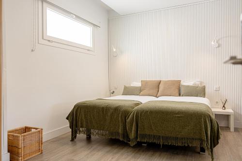 a bed in a white room with a window at Bambú Suites Vegueta Alquiler por Habitación in Las Palmas de Gran Canaria