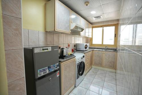 a kitchen with a refrigerator and a washer and dryer at Manchester Plaza Hotel in Dubai