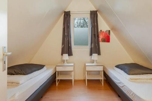 two beds in a room with a window at Boompieper I Beautiful family chalet with garden in Zwiggelte