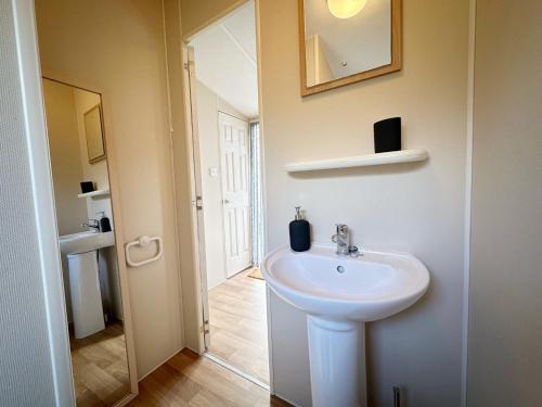 a bathroom with a white sink and a mirror at Chalet 588 op Recreatiepark De Wielen in Sint Maarten