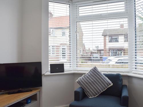 a living room with a blue chair and a large window at Sapphire Cottage in Lowestoft