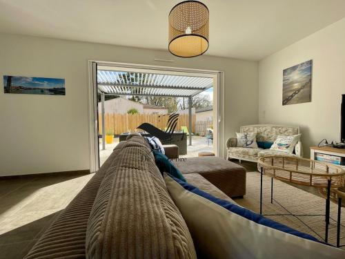 - un salon avec un grand canapé au milieu dans l'établissement Les Ganivelles - Belle maison neuve avec extérieur, à La Tremblade