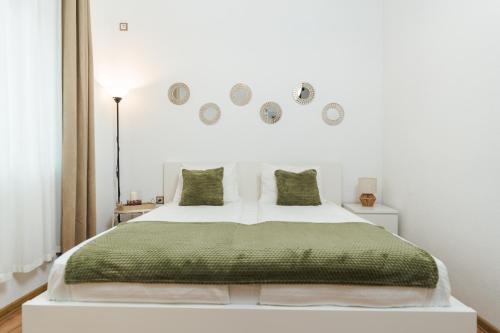 a bedroom with a white bed with a green blanket at Apartment Velik in Sandanski