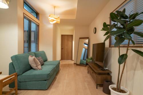 a living room with a green couch and a tv at The Peony Hotel Kyoto in Kyoto