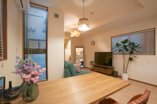 a living room with a dining room table and a television at The Peony Hotel Kyoto in Kyoto