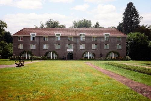 a large brick building with a grass field in front at Landgoed Ehzerwold in Almen