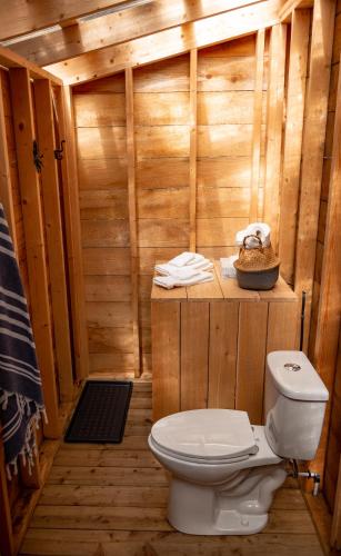 a bathroom with a toilet in a wooden cabin at Haida Gwaii Glamping in Tlell