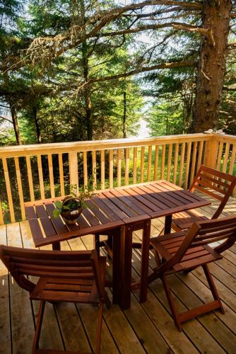 a wooden table and two chairs on a deck at Haida Gwaii Glamping in Tlell