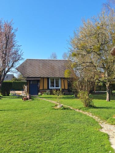 a yellow house with a grass yard and trees at La petite maison in Le Bosc-Roger-en-Roumois