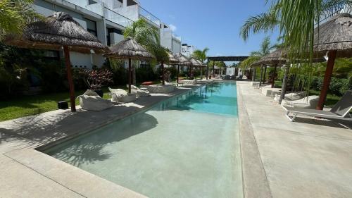 a swimming pool with lounge chairs and umbrellas at Tu Villa Adosada Lujo con Playa y Golf in Akumal