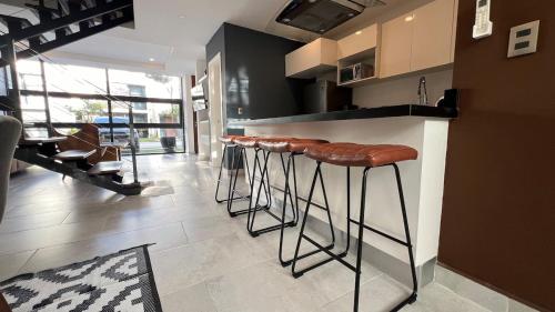 a kitchen with a bar with brown stools in it at Tu Villa Adosada Lujo con Playa y Golf in Akumal
