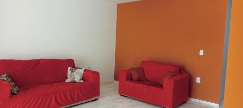two red chairs and a red couch in a room at Casa ideal 5 quatros sendo 3 suítes 2 km do centro in Bananeiras