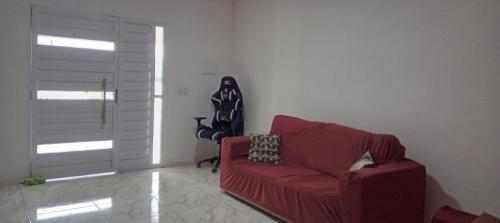 a living room with a red chair and a red couch at Casa ideal 5 quatros sendo 3 suítes 2 km do centro in Bananeiras