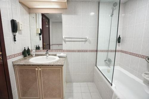迪拜Manchester Plaza Hotel的带水槽、淋浴和浴缸的浴室