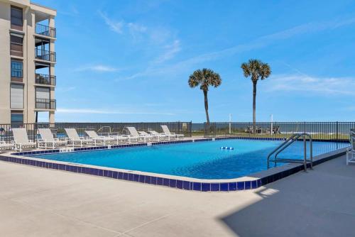 a large swimming pool with chairs and palm trees at Crescent Surf in Cedar Landing