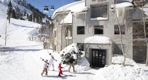 a group of people standing in the snow in front of a house at Palisades Tahoe Lodge Rentals Studio #109 in Olympic Valley
