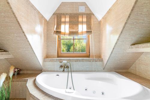 a large white tub in a bathroom with a window at Leśny Dworek Podjazy in Podjazy