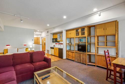 a living room with a red couch and a kitchen at Palisades Tahoe Lodge Rentals Studio #104 in Olympic Valley