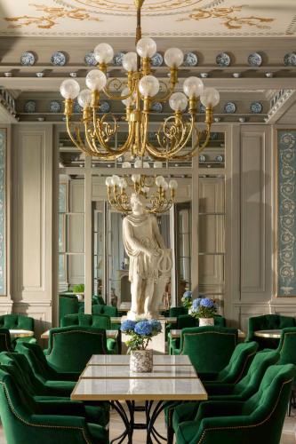 a large room with green chairs and a chandelier at Hotel Du Quai Voltaire in Paris
