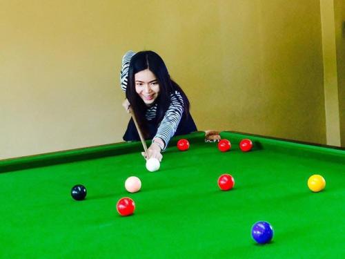 a woman playing pool with a cue on a pool table at บ้านไร่แสงเดือน รีสอร์ท in Ban Kha